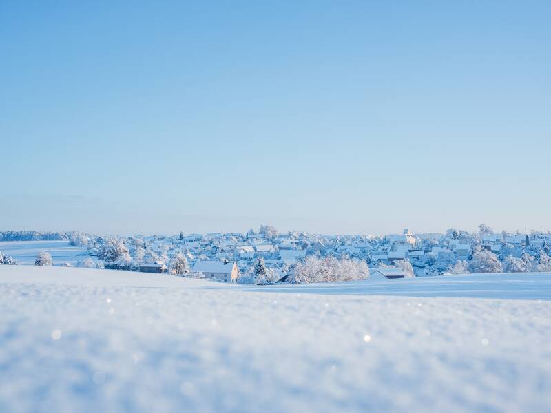 Eine verschneite Landschaft mit  Schönebürg in der Ferne liegend unter einem klaren blauen Himmel.