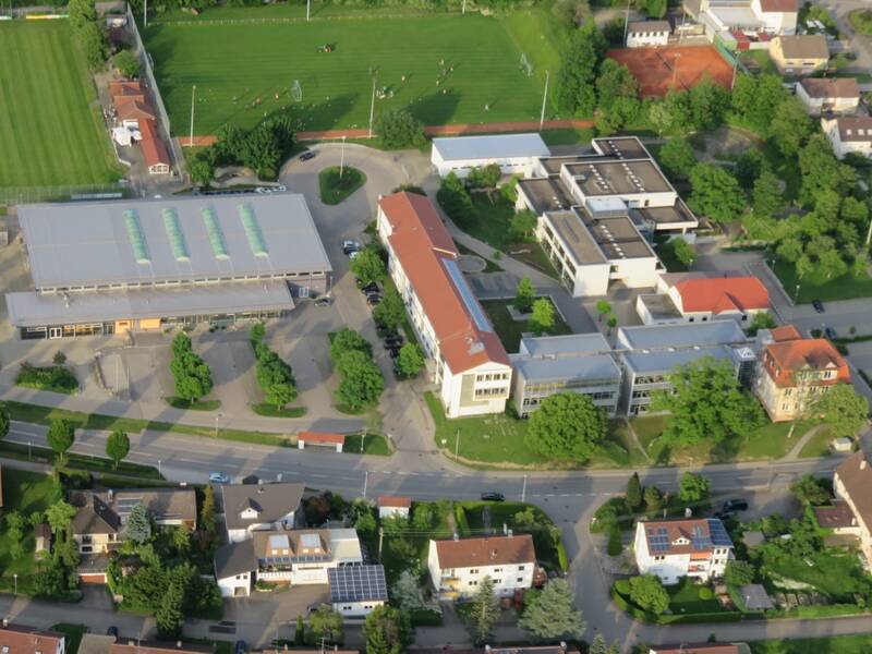 Luftbild vom Schulcampus in Schwendi, unten im Bild sind Wohnhäuser zu sehen, links im Bild ist die Sport- und Veranstaltungshalle, rechts die Max-Weishaupt Realschule und die Grund- und Werkrealschule, im Hintergrund ist der Sportplatz zu sehen