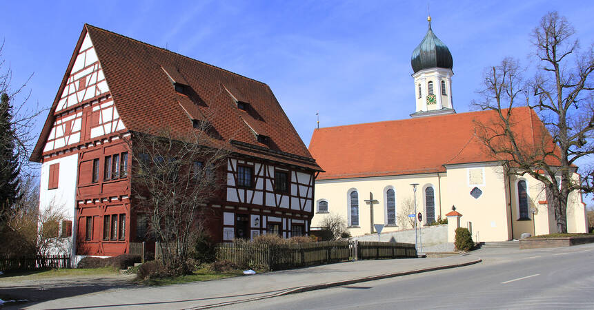 Kirche mit kleinem Bauerhaus daneben.